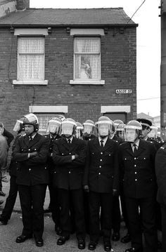 Black and white photo from the miner&apos;s strike showing policement in front of a terraced house